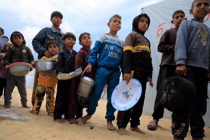 Niños palestinos hacen cola en una entrega de ayuda humanitaria en la ciudad de Rafá, situada en el sur de la Franja de Gaza, en la frontera con Egipto