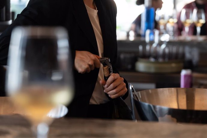 Un camarero abre una botella de vino
