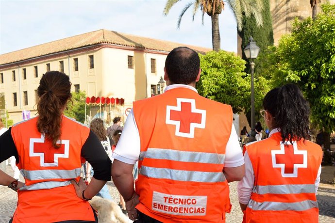 Voluntarios de Cruz Roja observan el discurrir de un paso de Semana Santa en Córdoba.