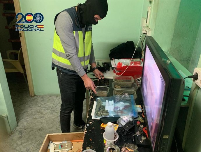 Un agente de la Policía Nacional junto a parte del material y la droga intervenidos