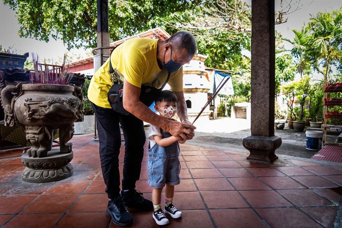 Archivo - June 4, 2022, Penang, Malaysia: A Buddhist man teaches his grandchild how to pray at a Chinese-Malaysian temple in Penang.