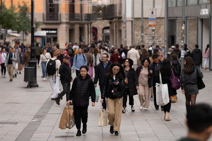 Archivo - Varias personas sujetan bolsas con compras en Barcelona.