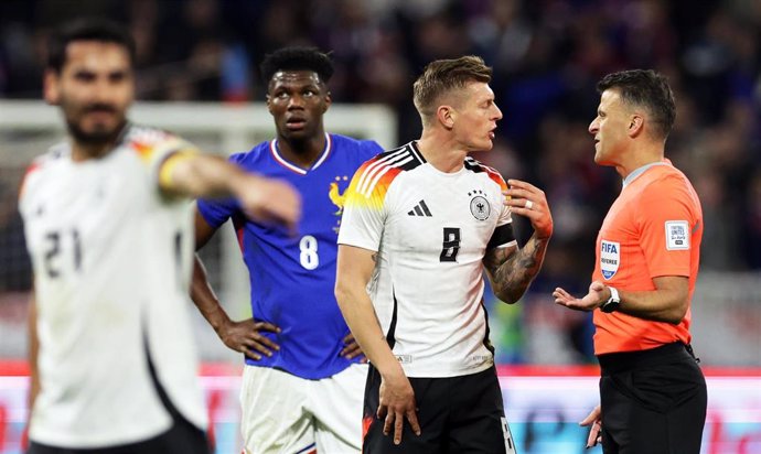 23 March 2024, France, Lyon: Germany's Toni Kroos (2-R) discusses with referee Jesus Gil Manzano from Spain during the International friendly soccer match between France and Germany at Groupama Stadium. Photo: Christian Charisius/dpa