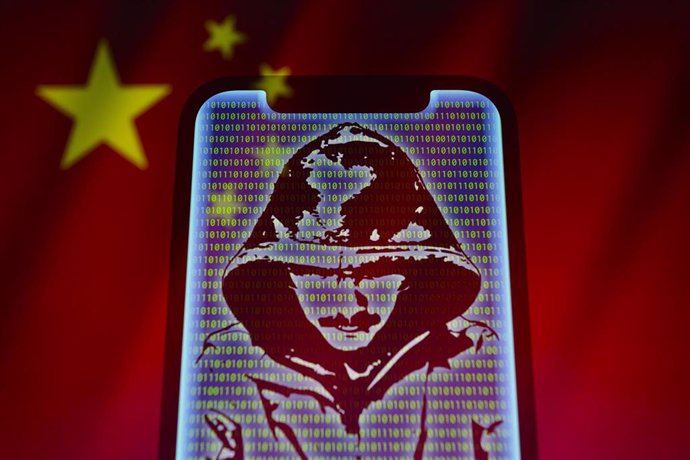 Archivo - Representación visual de los dígitos del código binario y de un hacker mostrados en un teléfono móvil con la bandera de China de fondo