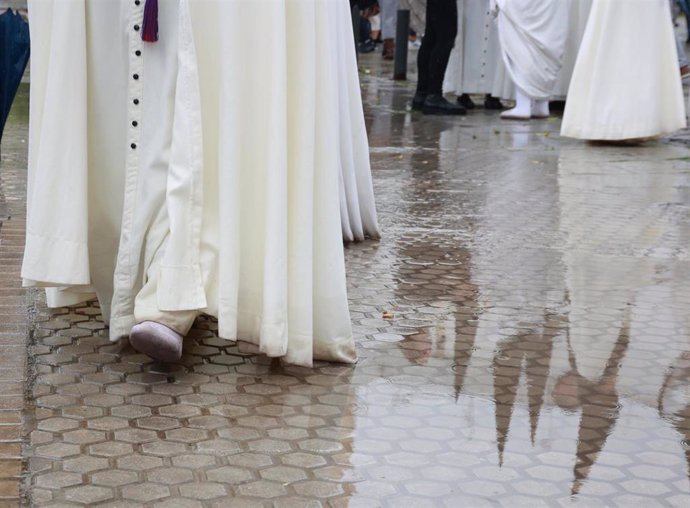Nazarenos de la Hermandad del Cautivo de San Pablo salen de la Iglesia tras suspenderse por la lluvia su estación de penitencia.
