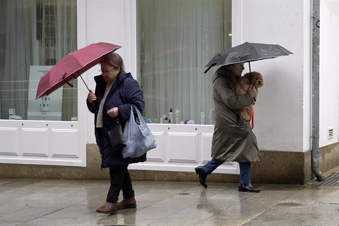 Archivo - Dos personas se refugian del viento con paraguas, a 8 de febrero de 2024, en A Coruña, Galicia (España). 