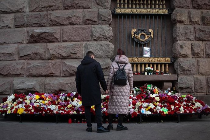 24 March 2024, Russia, St. Petersburg: A couple mourns at a spontaneous memorial to the victims of the terrorist attack at Crocus City Hall, organized on the spit of Vasilyevsky Island in the center of St. Petersburg. The terrorist group claimed respons