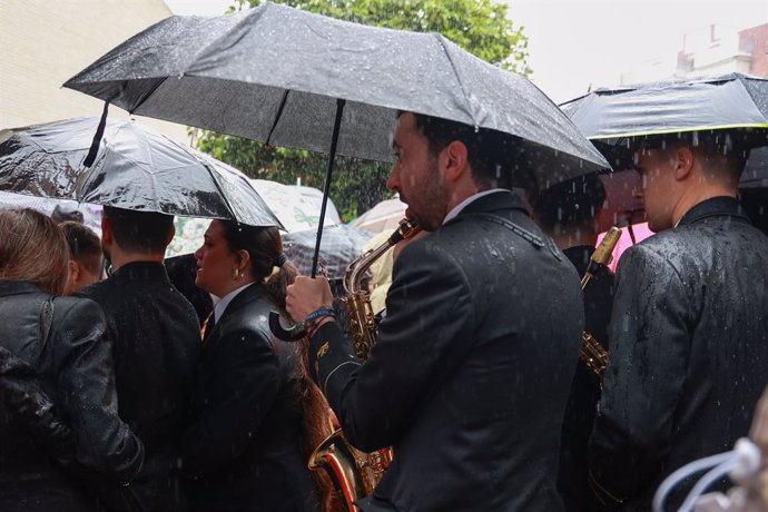 Músicos de la Hermandad del Cautivo de San Pablo se marchan tras suspenderse por la lluvia su estación de penitencia. A 24 de marzo de 2024, en Sevilla (Andalucía, España).