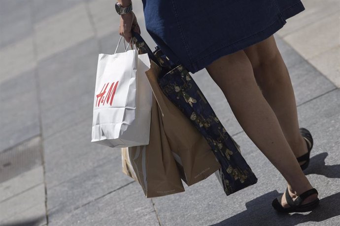 Archivo - Una mujer pasea cargada con varias bolsas, una de ellas perteneciente a la tienda H&M a 26 de junio de 2020. 