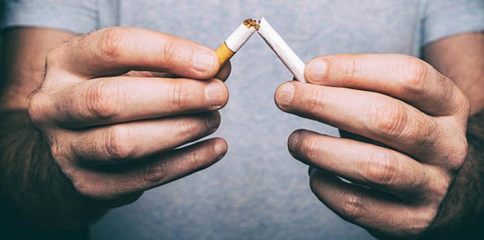 Una persona rompe por la mitad un cigarro de tabaco