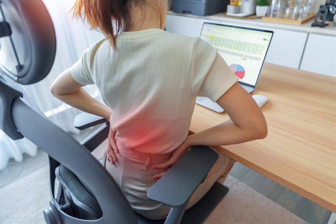 Archivo - Woman having back body pain during work long time on workplace. Due to Piriformis, Low Back, waist ache, lumbago, kidney, rheumatism and Spinal Compression. Office syndrome and Ergonomic concept