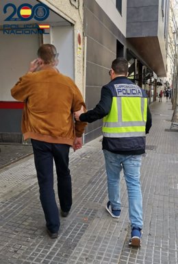 El detenido por la posesión de 2,2 millones de archivos pedófilos, entrando en dependencias de la Policía Nacional en Palma, escoltado por un agente del Grupo de Delitos Tecnológicos y Delincuencia Económica.