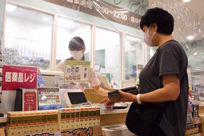 Archivo - July 2, 2020, Tokyo, Japan: A woman wears a facemask as she pays at a register separated by plastic curtains at a pharmacy in AEON Mall amid Covid-19 pandemic..Following Tokyo's reopening, 107 new cases of the novel coronavirus (COVID-19) have b