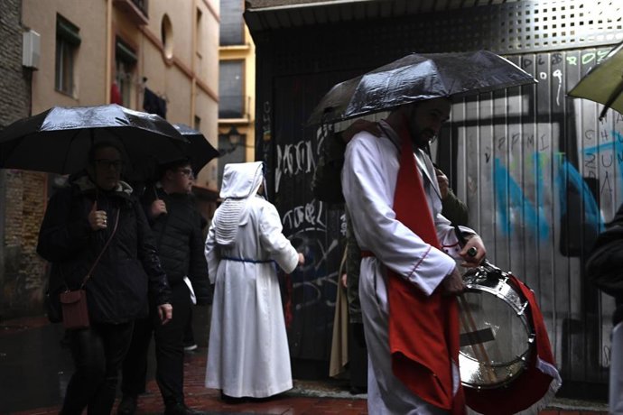 Varias personas con paraguas tras el anuncio de que se tiene que cancelar la Procesión del Santo Entierro a causa de la climatología adversa (lluvia y viento), a 29 de marzo de 2024, Zaragoza, Aragón (España).