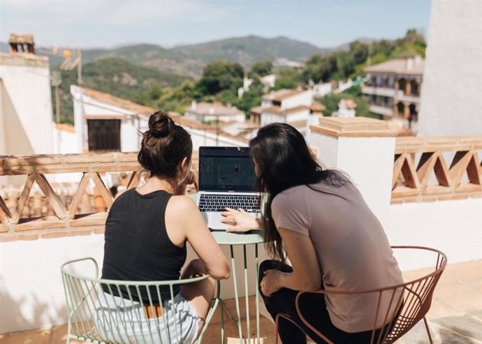 Imagen de archivo de dos jóvenes con un ordenador portátil en un entorno rural.