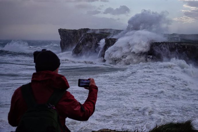 Archivo - Una persona toma fotografías del oleaje en Llanes, Asturias (España). 