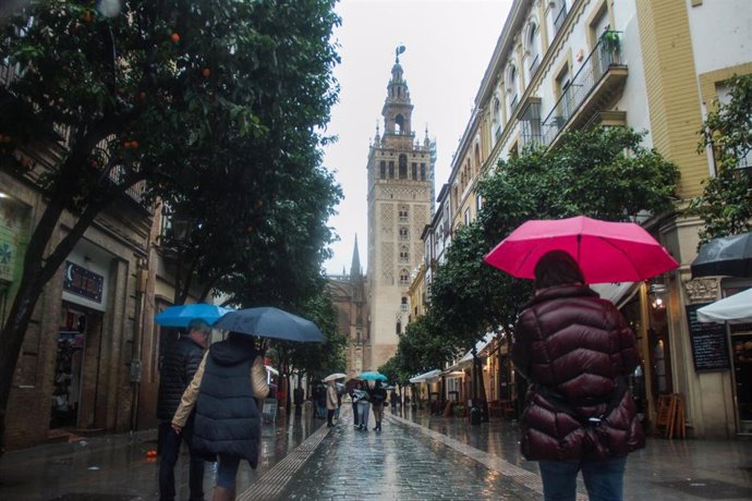 Archivo - Varias personas se protegen de la lluvia bajo sus paraguas en Sevilla (Andalucía, España)