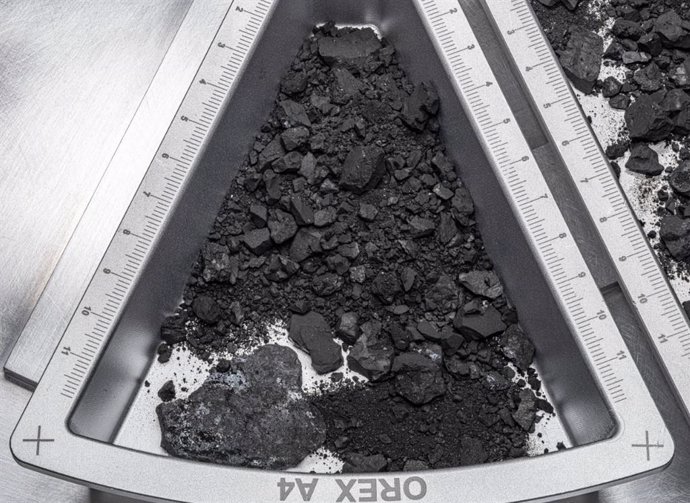 Una vista de arriba hacia abajo de uno de los contenedores que contienen rocas y polvo del asteroide Bennu, con una escala de hardware marcada en centímetros.
