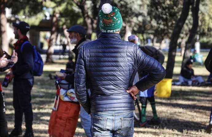 Archivo - Varias personas comen durante el reparto de alimentos a personas sin recursos, en el viejo cauce del río Turia.