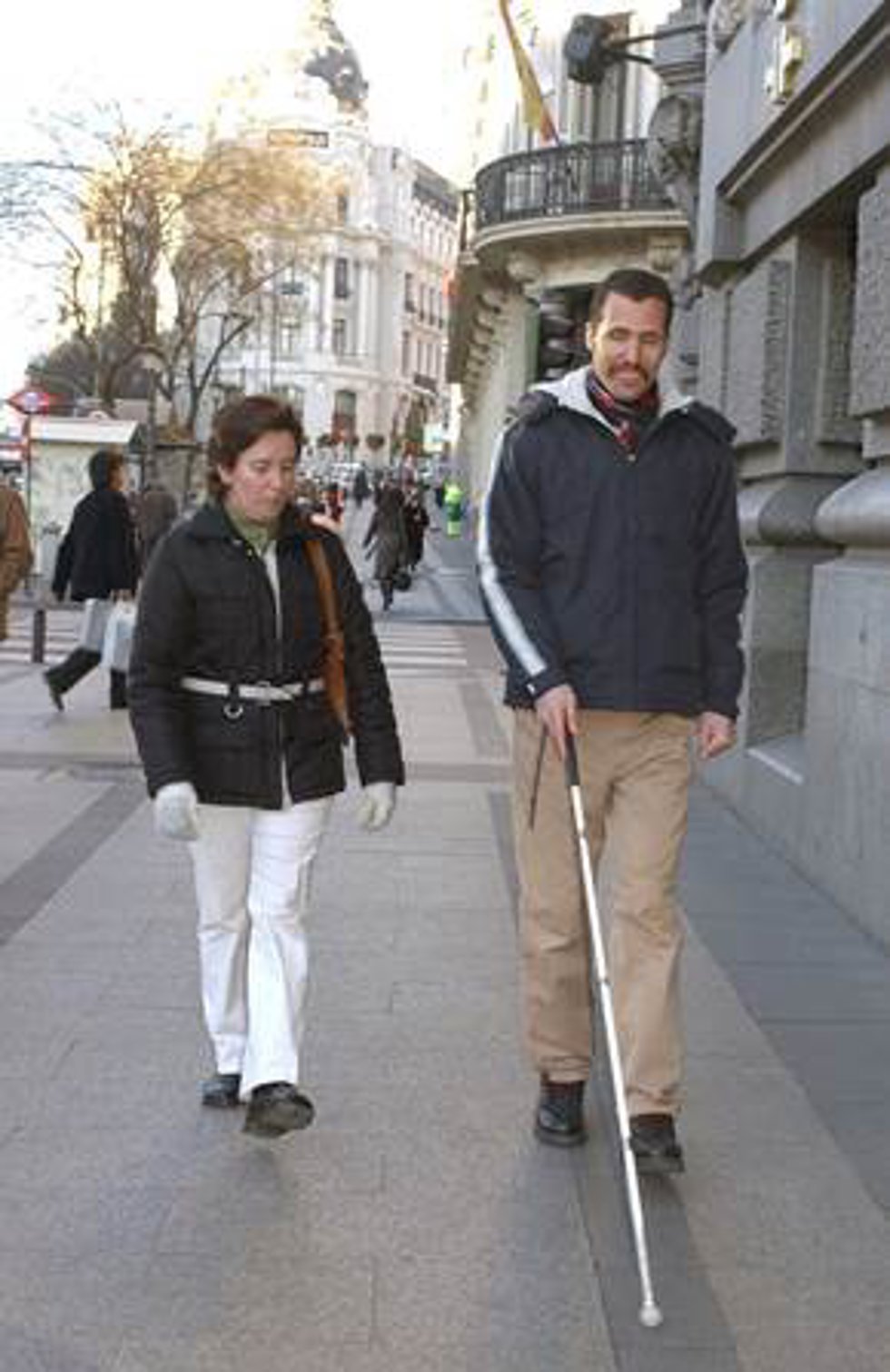 Técnico de rehabilitación de la ONCE enseñando a usar el bastón blanco a una persona extranjera.
