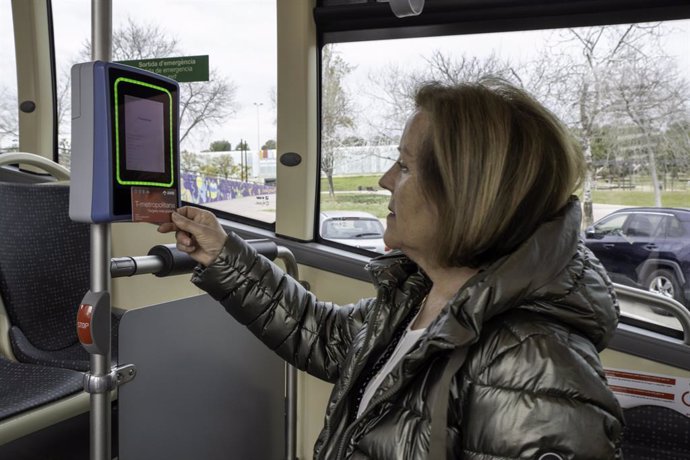 Archivo - Una dona valida una T-metropolitana al lector d'un autobús.