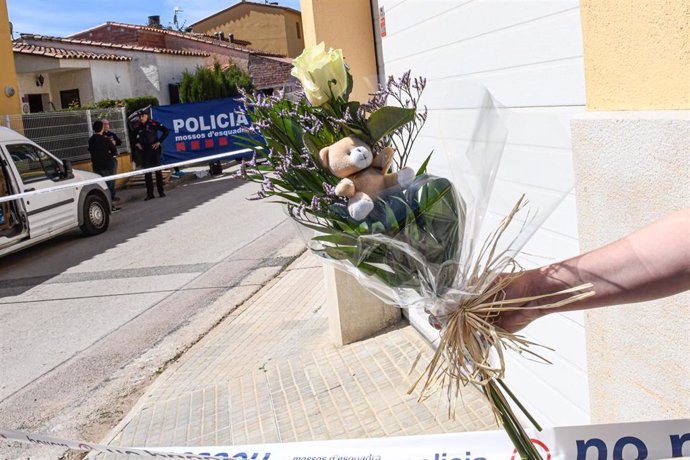 Una persona leva un ramo de flores y un peluche donde un hombre ha matado a su hijo y ha apuñalado a la madre en Bellcaire (Girona)