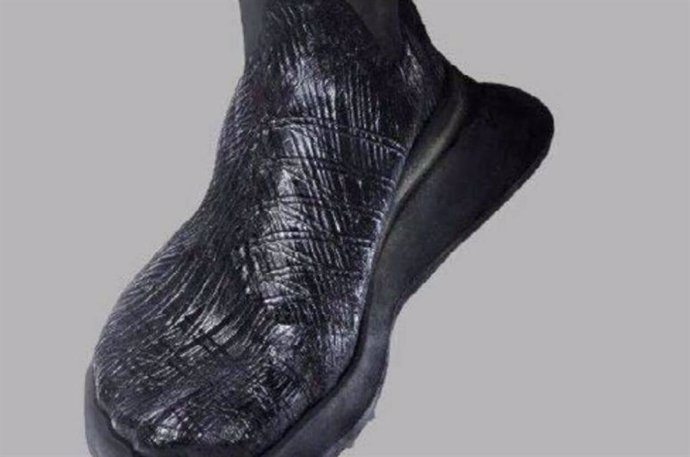 Un prototipo de parte superior de zapato finalizado producido a partir de una lámina BC con forma de melanina con hilo integrado que se envuelve alrededor de una horma con forma de pie y se coloca sobre una suela de zapato.