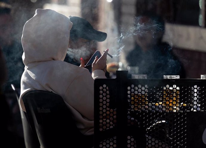 Archivo - Una persona fumando en una terraza.