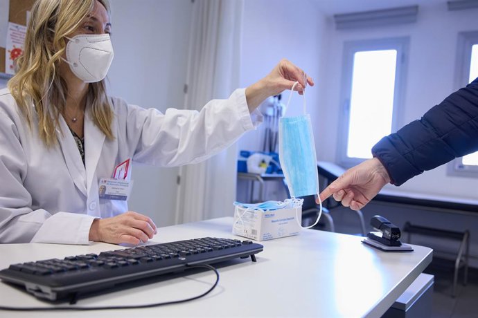 Archivo - Una sanitaria ofrece una mascarilla a un paciente en el centro de salud 'Isla de Oza', a 11 de enero de 2024, en Madrid (España). 