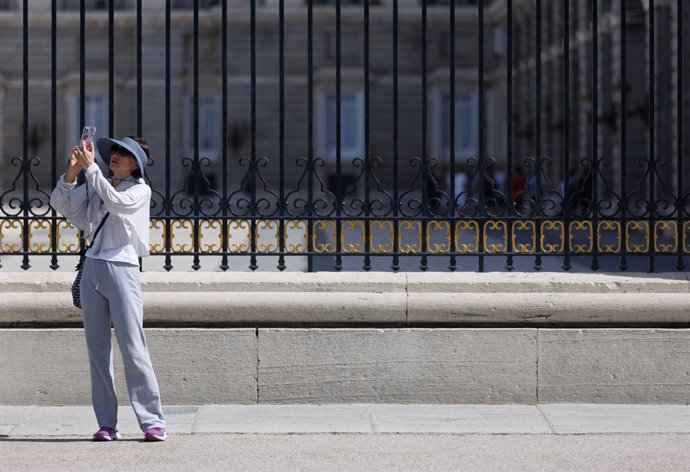 Archivo - Una turista tomando fotografías frente al Palacio Real de Madrid.