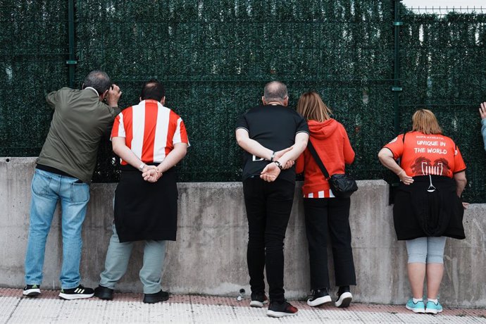 Varios aficionados observan desde una valla las instalaciones del Athletic Club de Bilbao, a 5 de abril de 2024, en Lezama, Vizcaya, País Vasco (España). Mañana, 6 de abril, el Estadio La Cartuja de Sevilla acoge, por quinta vez consecutiva, la final de l