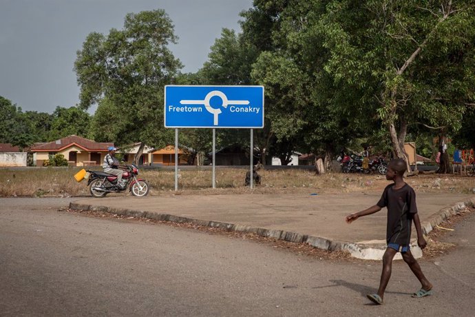 Archivo - April 1, 2021, Mafaray, Sierra Leone: A boy walks past a signpost that points to both Sierra Leone capital Freetown and Guinea's capital Conakry..The latest Ebola outbreak in Guinea was declared in February 2021.