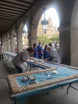Los voluntarios de Autismo Segovia en el corte previo de las raciones, con el ponche ya terminado y  montado en los soportales de la Plaza Mayor.