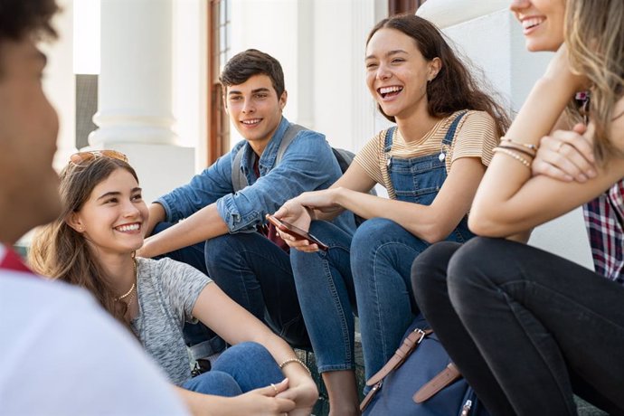 Archivo - Amigos adolescentes sentados juntos y riendo