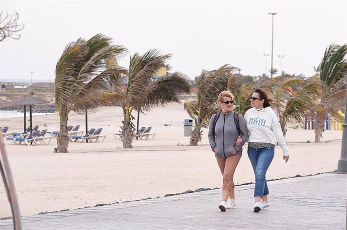 Archivo - Dos mujeres pasean por una playa de Fuerteventura con viento, a 27 de diciembre de 2022, en Fuerteventura, Las Palmas, Islas Canarias (España). El viento de hoy ha causado más de 125 incidentes, como caídas de ramas de árboles, palmeras, postes 