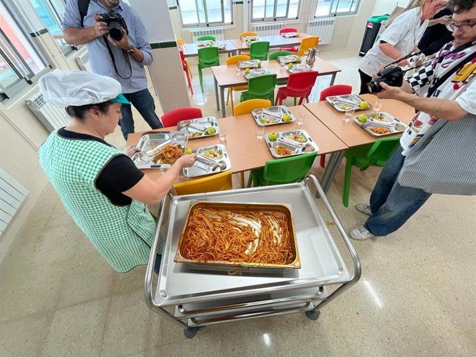 Una trabajadora prepara bandejas de comedor escolar