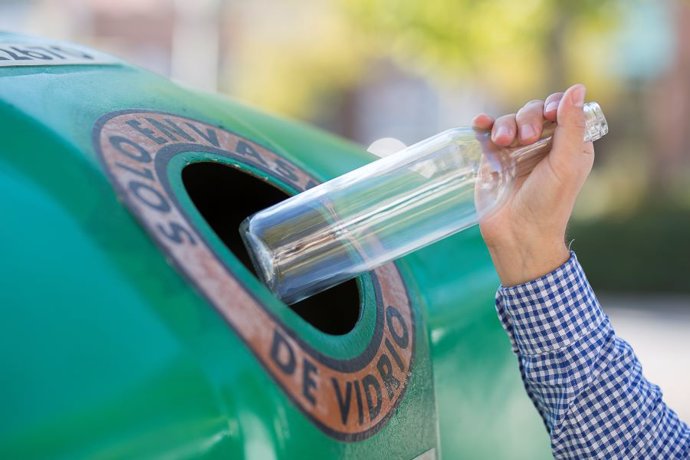 Una persona deposita una botella de cristal en uno de los contenedores verdes de Ecovidrio.