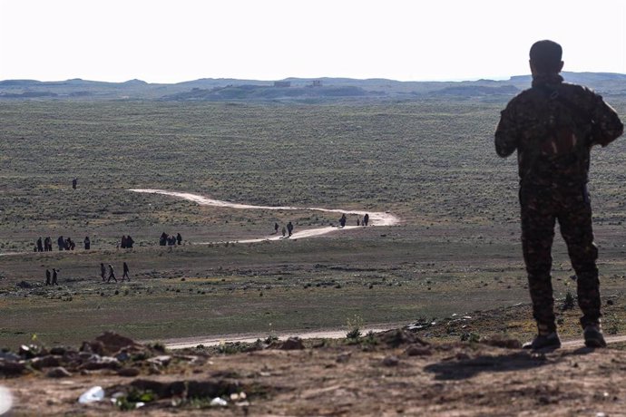 Archivo - Imagen de archivo de un combatiente de las FDS que observa cómo los civiles huyen de la aldea de Baghouz, controlada por Estado Islámico, en la provincia oriental siria de Deir Ezzor