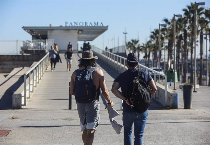 Archivo - Varias personas caminan frente a la playa de la Malvarrosa, en València. 