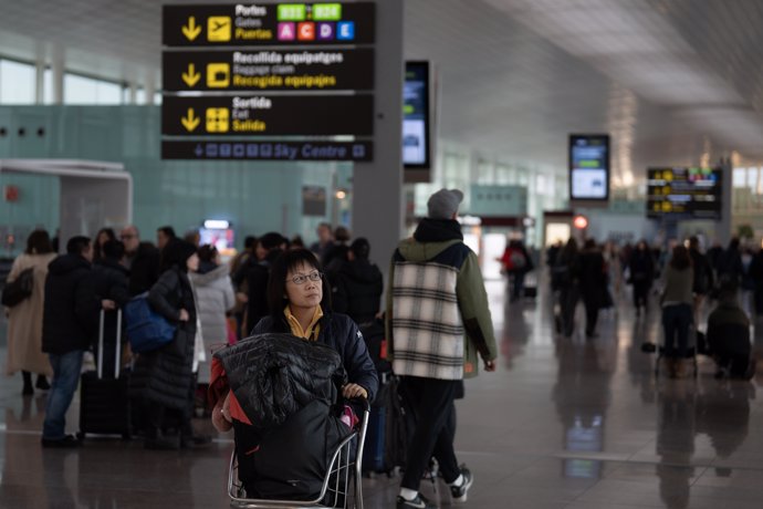 Dos personas esperan sentadas frente a un avión aparcado en la pista del aeropuerto de El Prat, a 19 de enero de 2023, en el Prat de Llobregat, Barcelona, Catalunya (España).