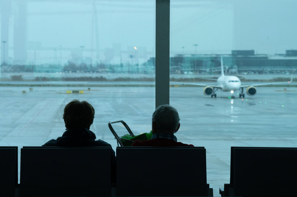 Dos personas esperan sentadas frente a un avión aparcado en la pista del aeropuerto de El Prat, a 19 de enero de 2023, en el Prat de Llobregat, Barcelona, Catalunya (España).