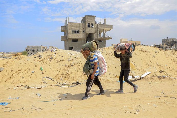 Palestinos vuelven con sus pocas pertenencias a la ciudad de Jan Yunis, en el sur de la Franja de Gaza, tras la retirada de las tropas del Ejército de Israel