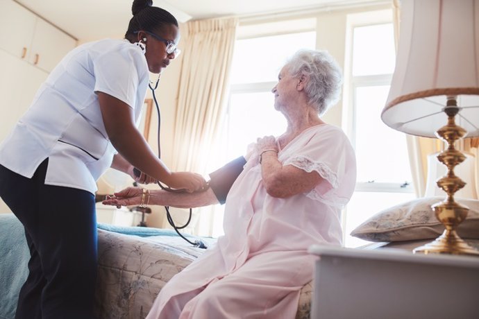 Archivo - Female nurse checking blood pressure of a senior woman