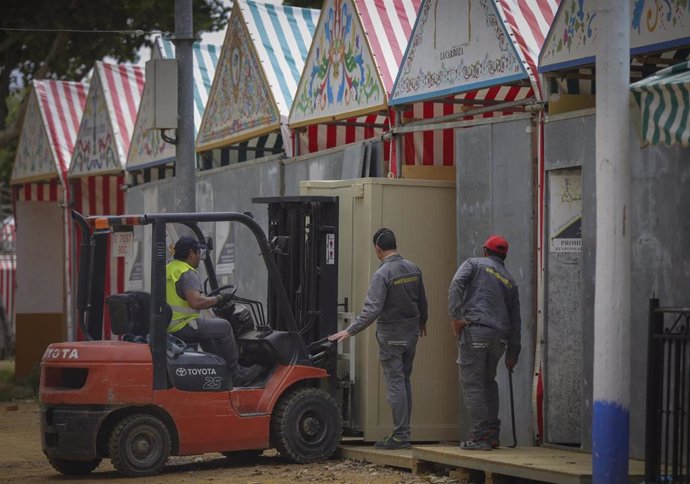 Archivo - Operarios desmontan una caseta en las instalaciones de la Feria de Abril de Sevilla, en foto de recurso.