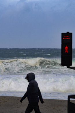 Archivo - Una persona camina delante de las olas durante el frente meteorológico, a 23 de febrero de 2024, en A Coruña, Galicia (España). La Agencia Estatal de Meteorología (Aemet) decretó un aviso naranja por temporal costero en el litoral gallego que ya