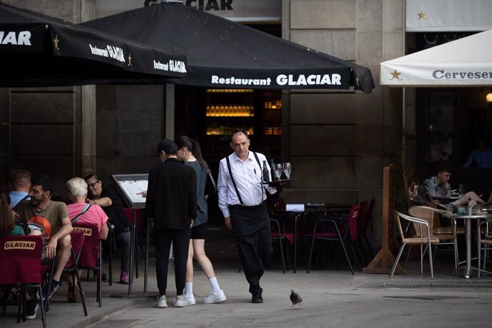 Archivo - Un camarero sostiene una bandeja en la plaza Real de Barcelona.