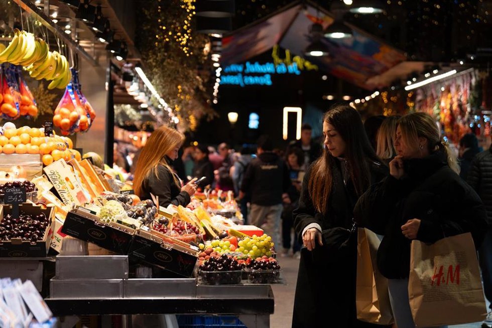 Archivo - Varias personas miran el género en el Mercado de la Boquería
