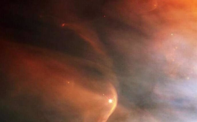 Imagen infrarroja de la onda de choque (arco rojo) creada por la enorme estrella gigante Zeta Ophiuchi en una nube de polvo interestelar