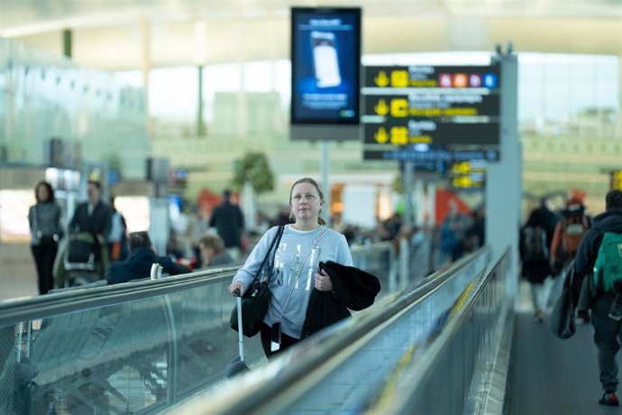 Archivo - Una mujer camina con su maleta en una cita en el aeropuerto de El Prat.