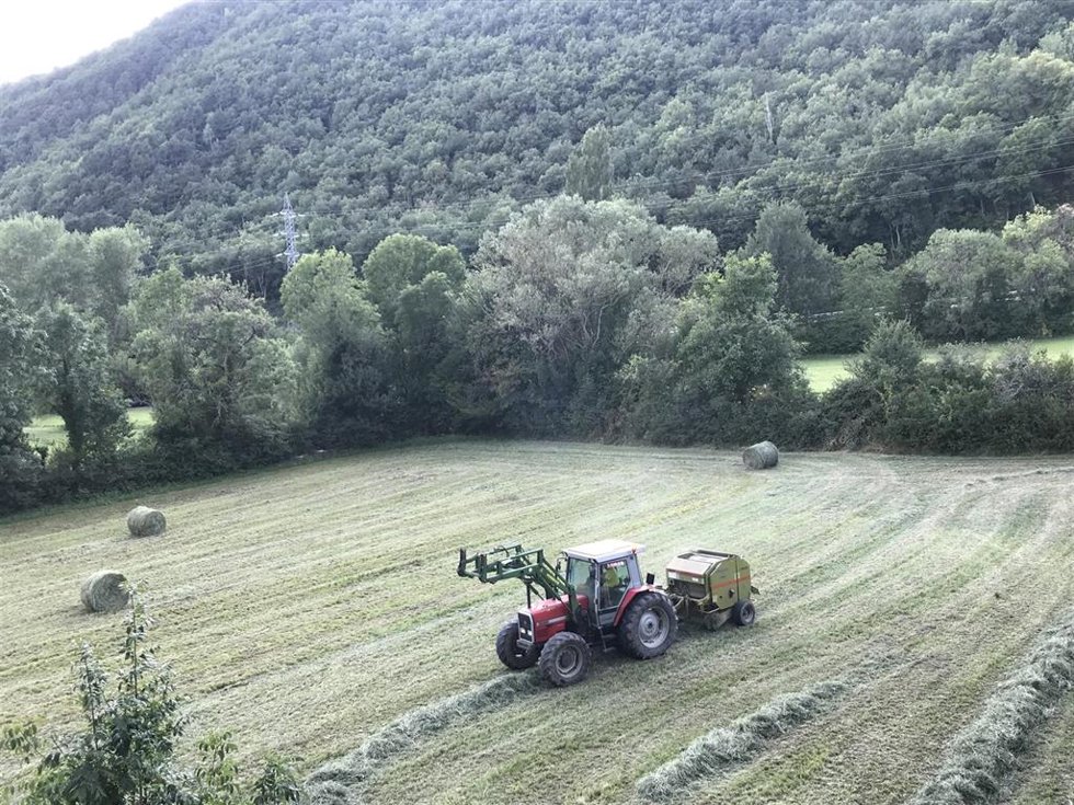Archivo - Un tractor recoge pacas de hierba